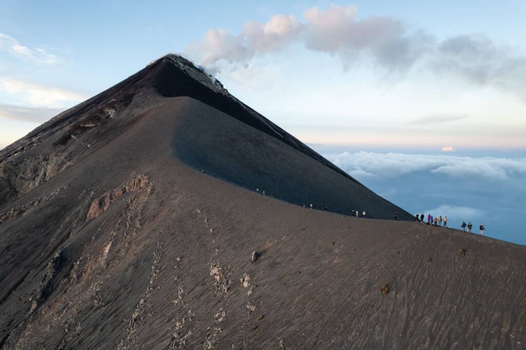 Drone shot of the volcano Fuego at the sunrise. You can see people on the summit admiring the smoke coming out of the volcano