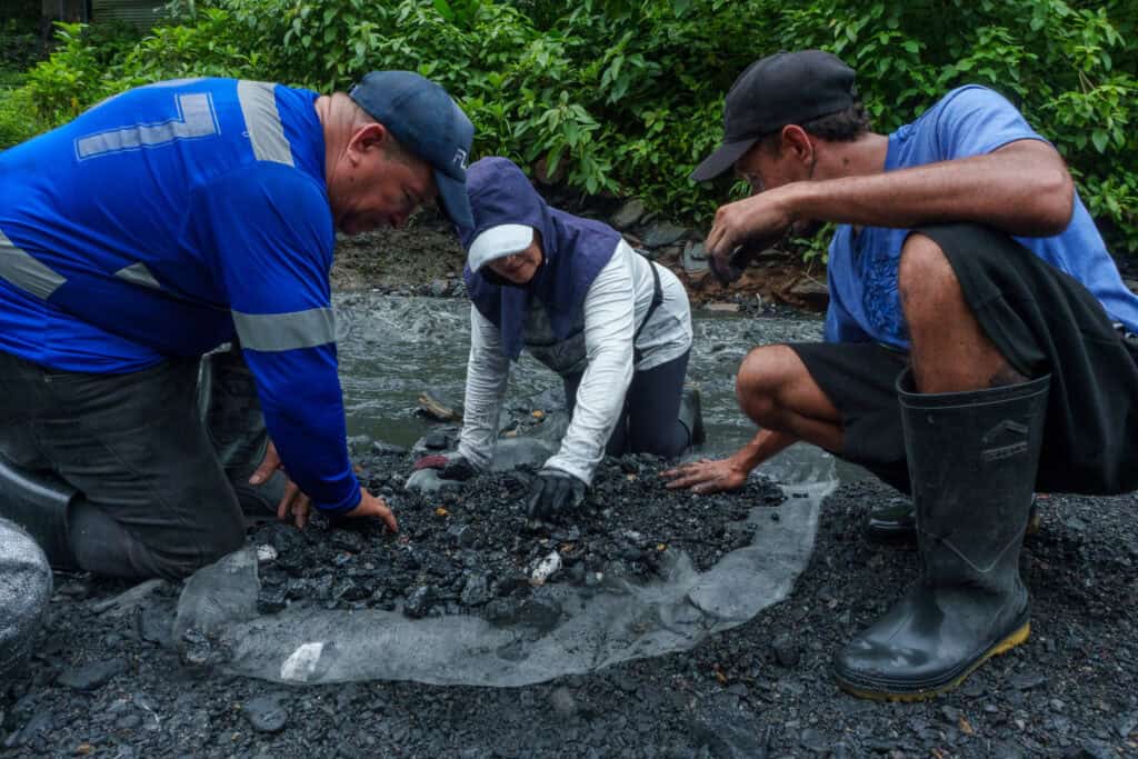 Three miners are looking carefully into the rocks trying to find emeralds, at the mines of Muzo