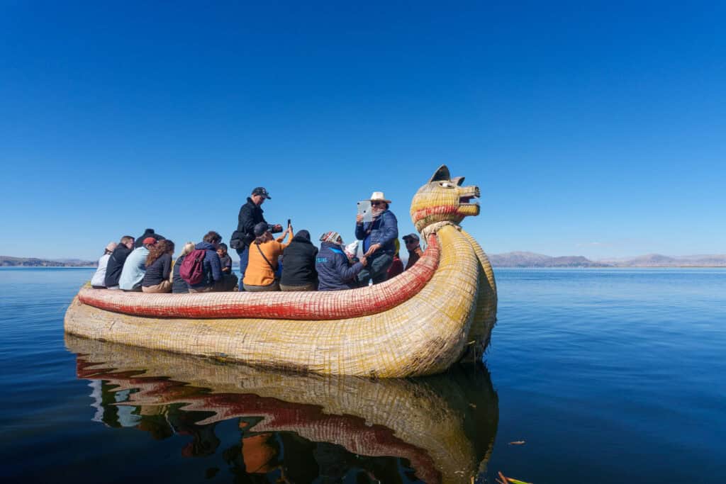 Tourist group on a traditional Uros community boat , on the lake titicaca, Peru
