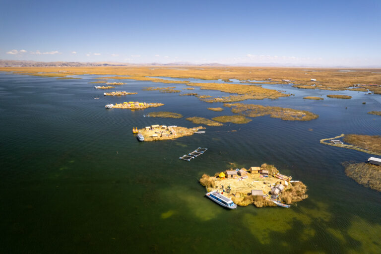 Aerial view of many floating island from Uros community with turists group on each of them visiting and discovering their lifestyle