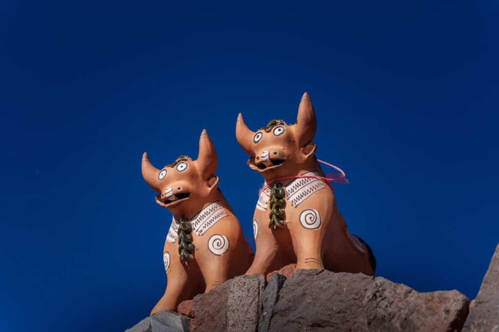 Two bull statues on the top of a house as it's a traditional decoration and protection for the house in the andean mountain