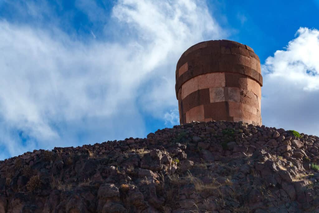 View from the bottom of the hill looking the main tomb at Sillustani, with the blue sky with some clouds