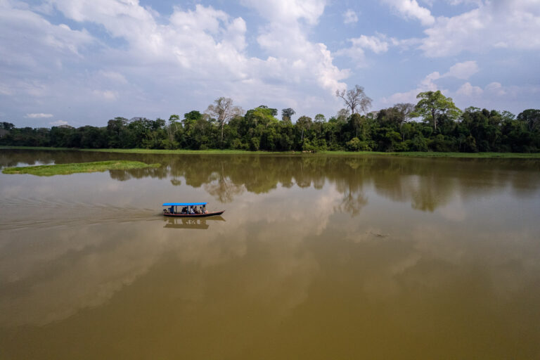 Sustainable bolivia boat and researchers cruising on the san jose lake in Bolivia. we can see the amazon jungle in the background.