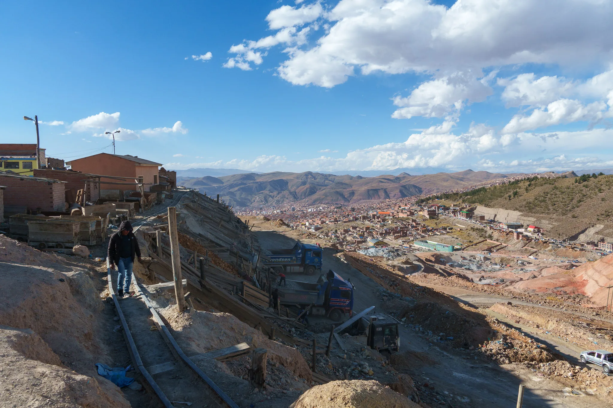 Miner walking on the rails, on Cerro Rico mountain. we can see the city of Potosi in the background.