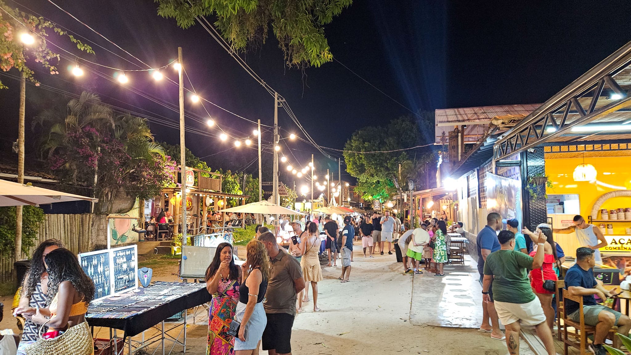 Barra Grande main street at night. People are walking the street and going to restaurants or buying souvenirs.