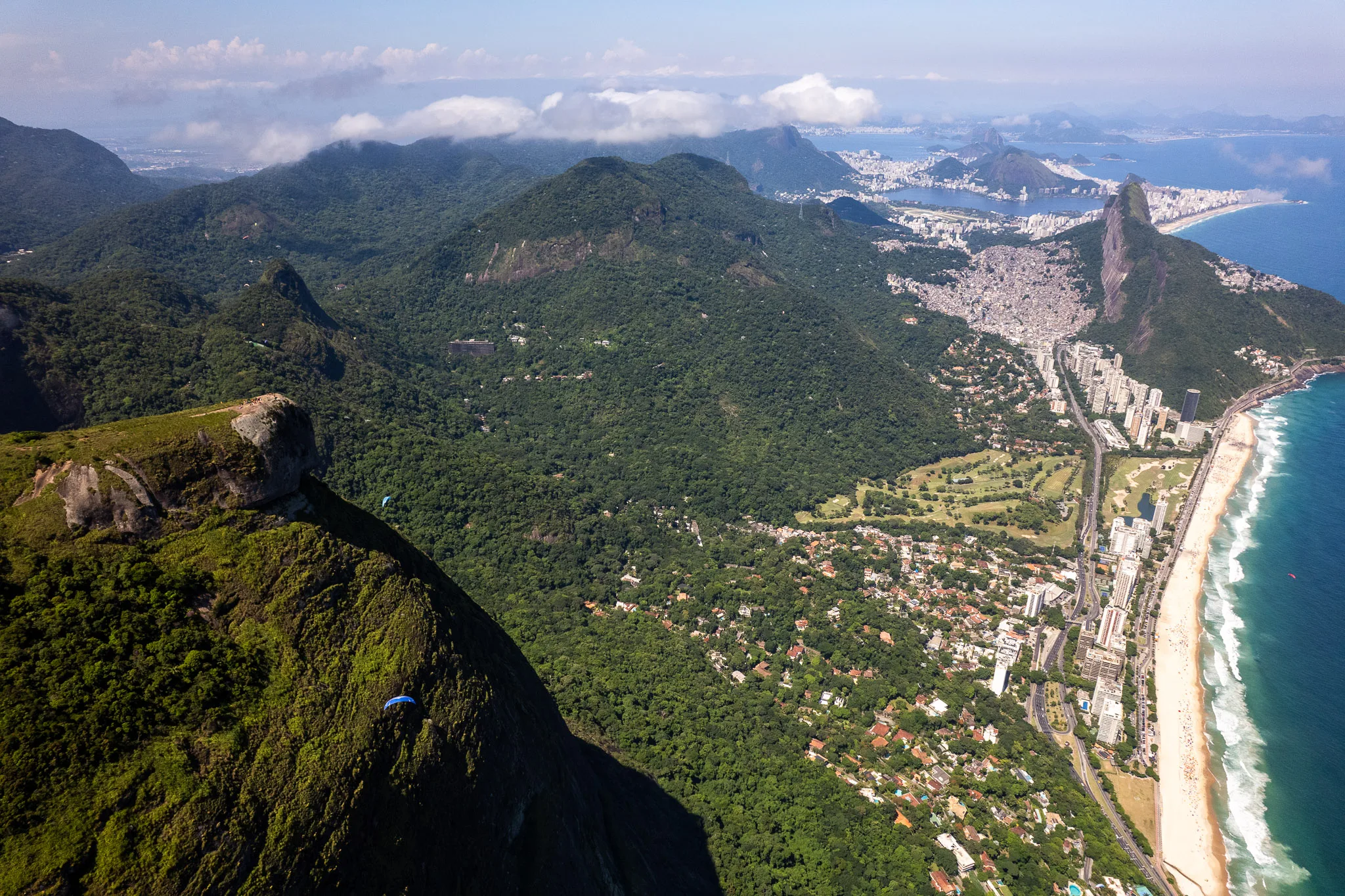 Aerial view of Pedra d aGavea with paraglider next to it. we see Dosi irmaos in the background as well as the favela Rocinha. Rio de Janeiro, Brazil.