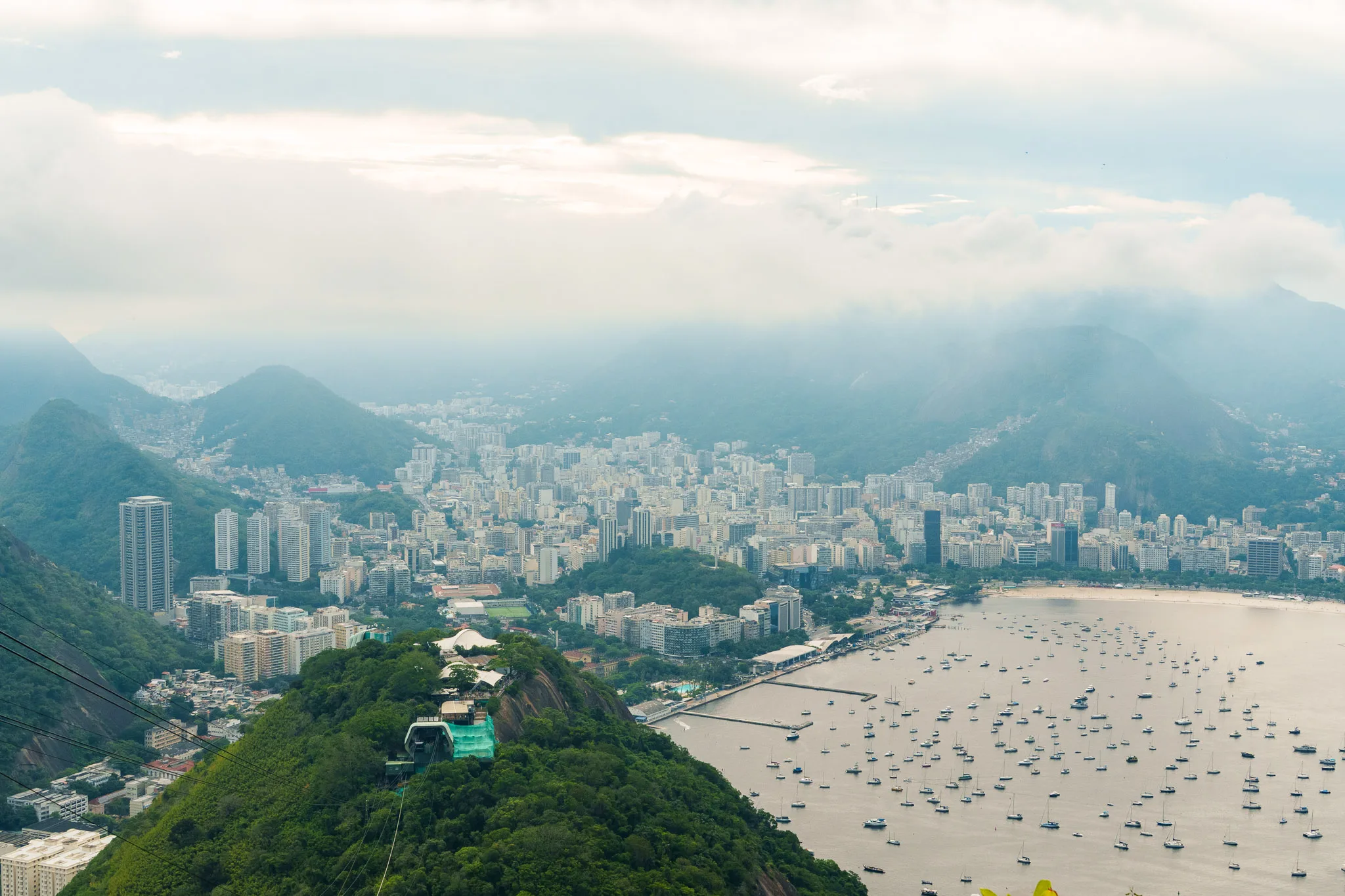 viewpoint of the Sugarloaf in rio d ejaneiro brazil. you can see the city below and fog covering the mountains all around.