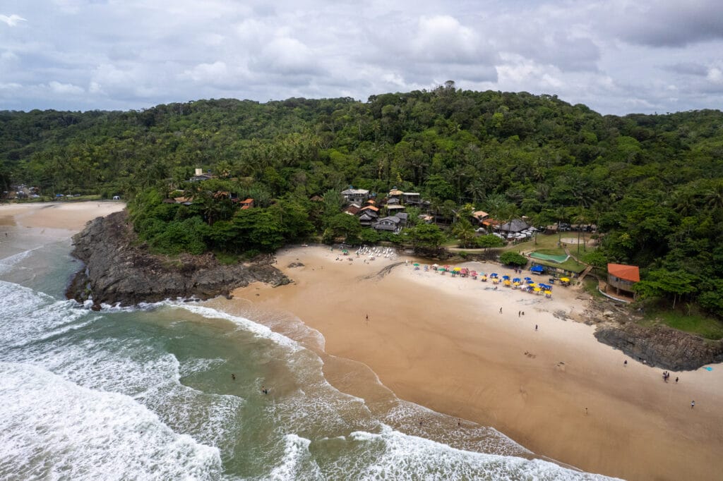 Aerial view of the Tiririca beach near the town of Itacaré, Brazil. the sea meets the jungle, the ebach is small with parasol, chairs and people.
