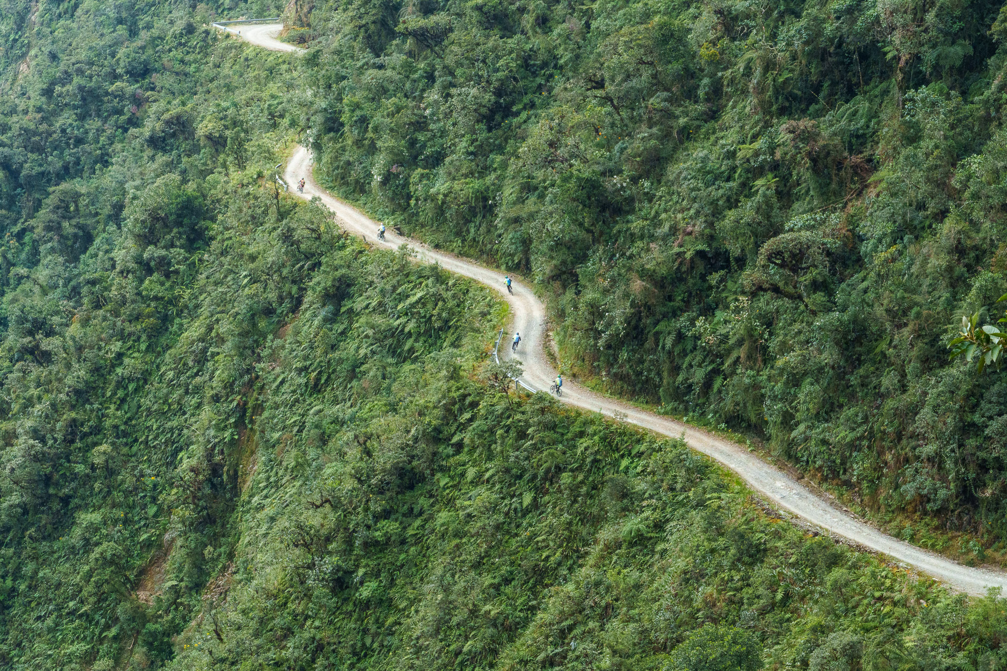 Zoom of the Death Road with biker riding down the road. Each bikers let few meters in front in case of emergency breaking or falling of the one in front of you.