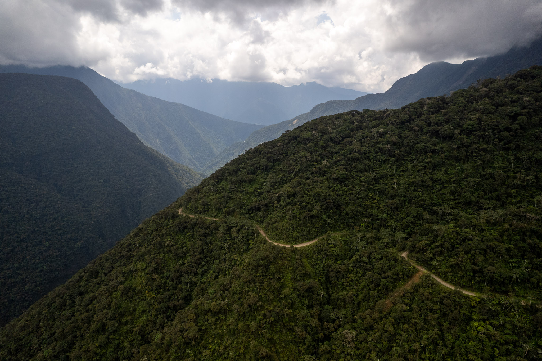 Aerial view of the Death road valley. We can see the Death Road with its curve passing through the dense green valley.