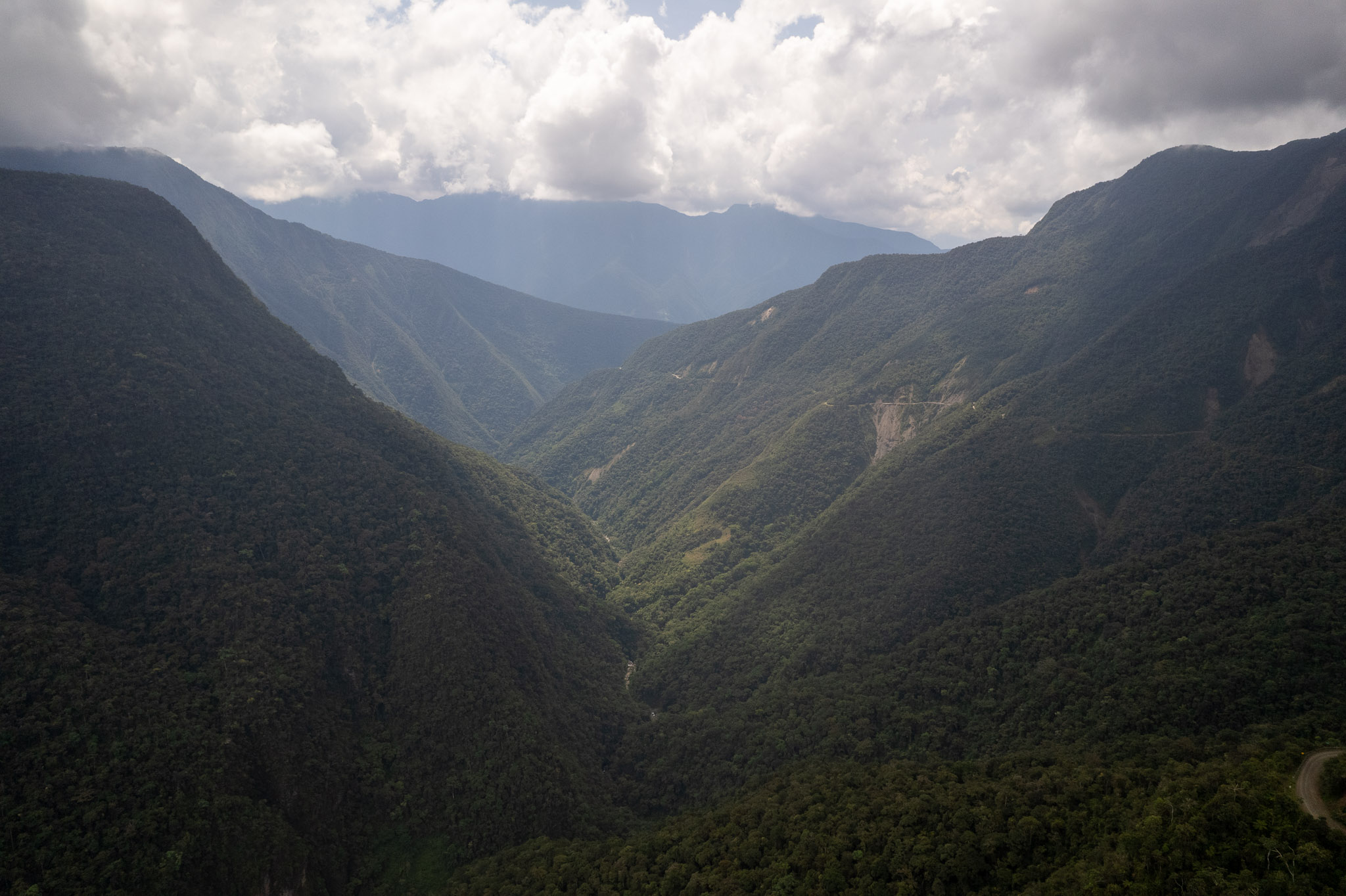 Aerial view of the Death Road valley. The valley is green, full of trees and plants, signaling the begining of the yungas region