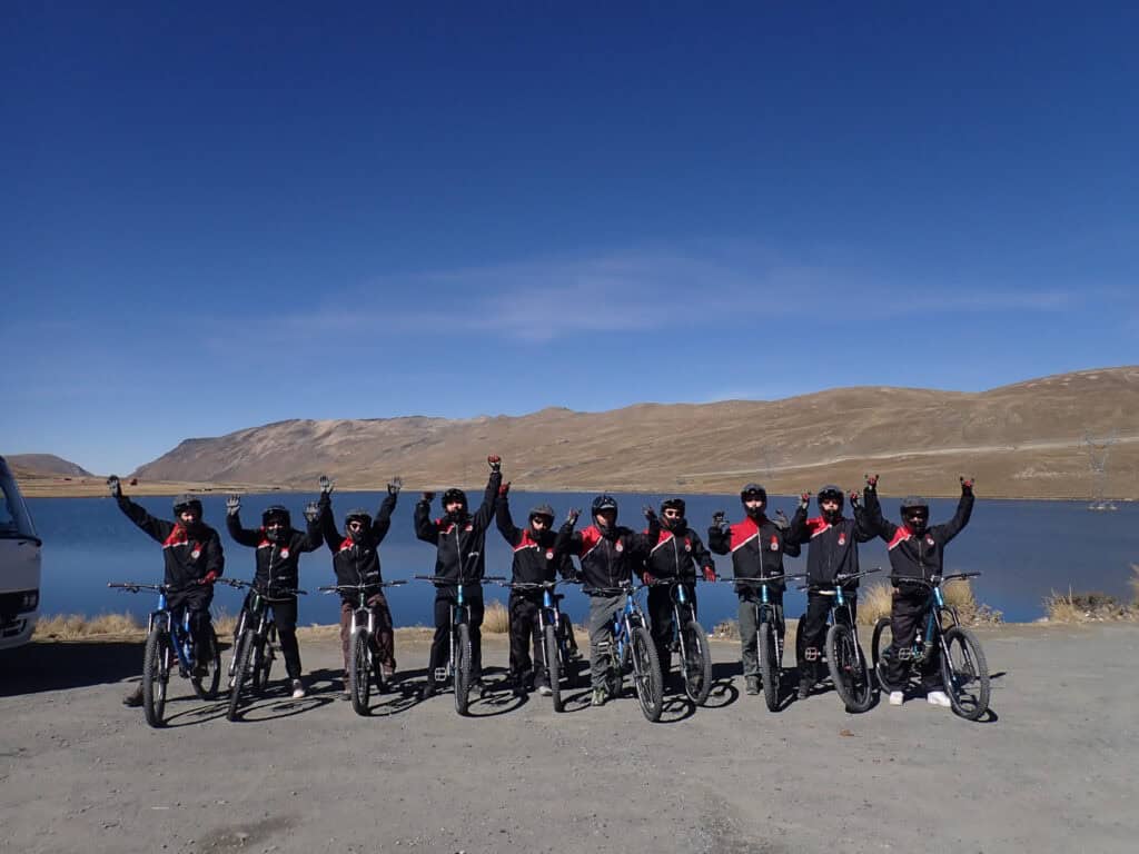 Gravitiy Bolivia team at the beginning of the Death Road Tour in the morning. in the background there is the "Laguna Estrellani"