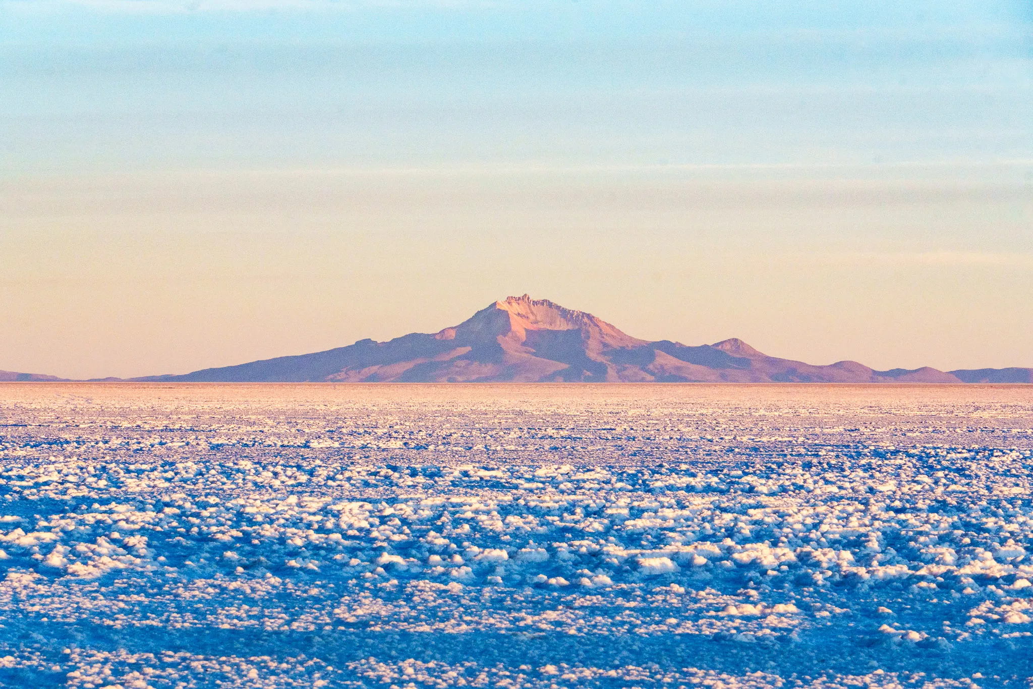 Salar de Uyuni in the sunrise with a mountian in the background