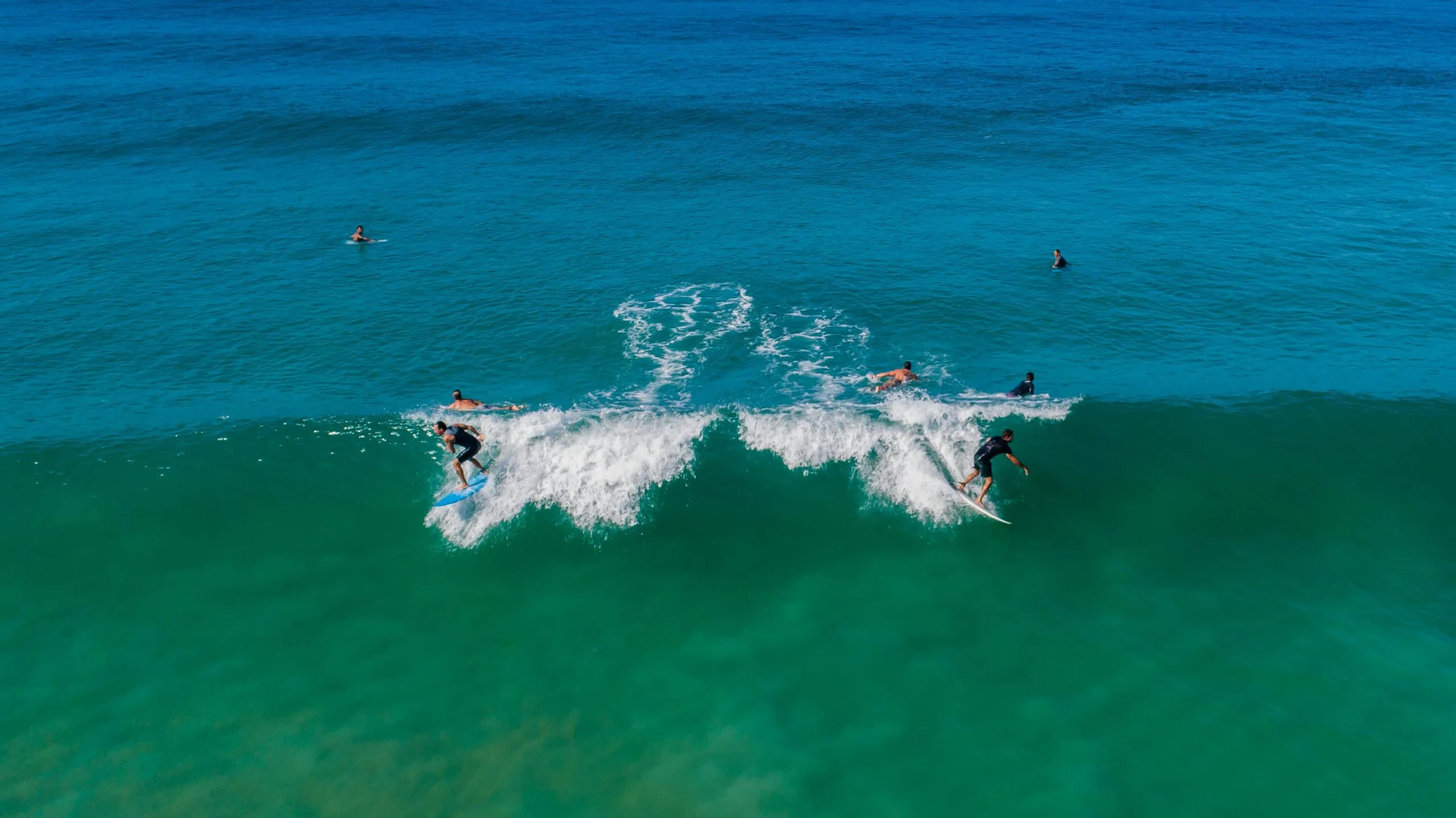 people doing surf. two people take the same waves on opposite sides