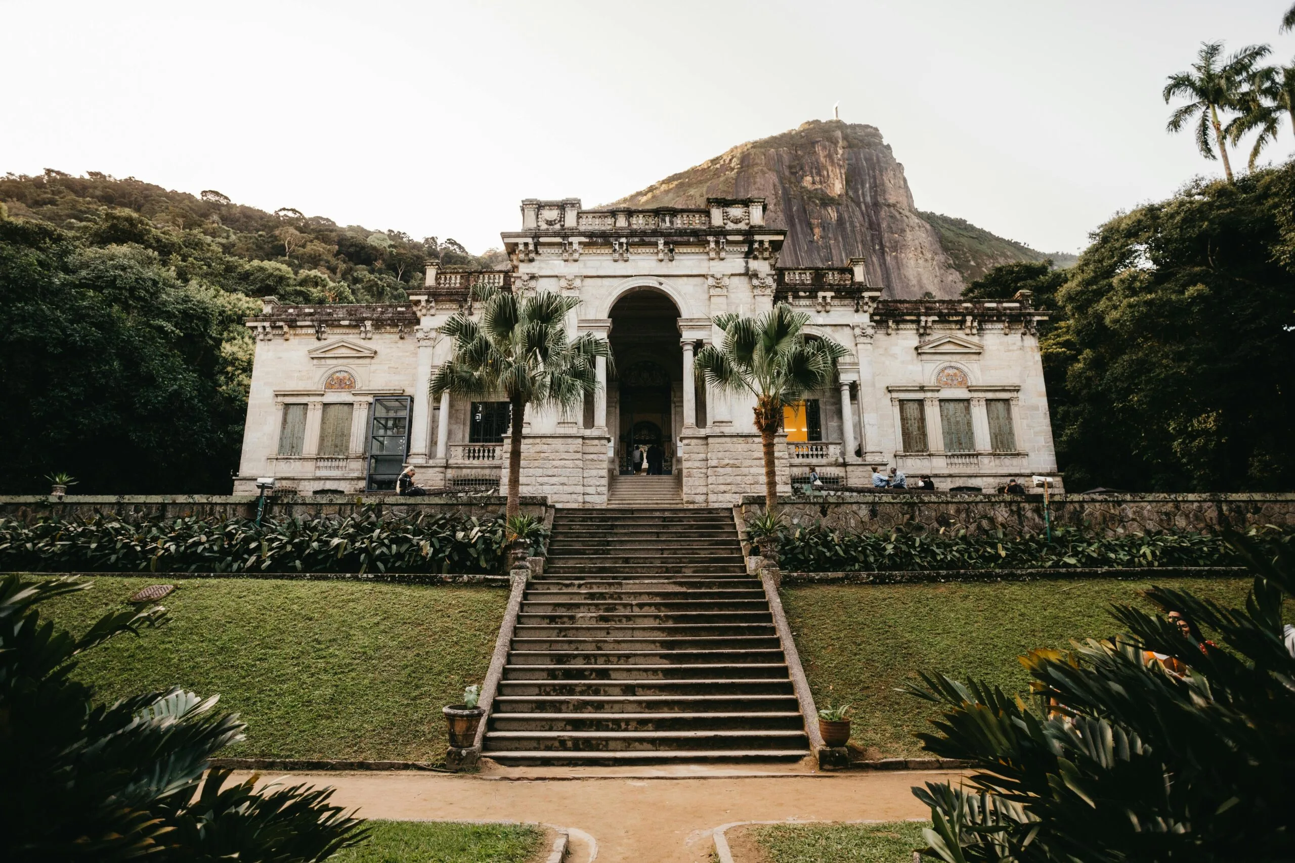 Parque Lage and its colonial house. there is the corcovado in the background. palm trees and trees all round the house.