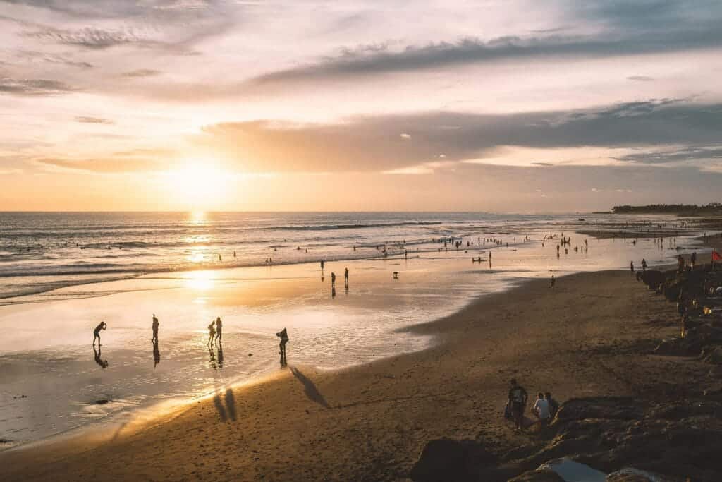 Beach at Kuta, Bila, Indonesia, during the sunset. People are on the ebach playing or walking.