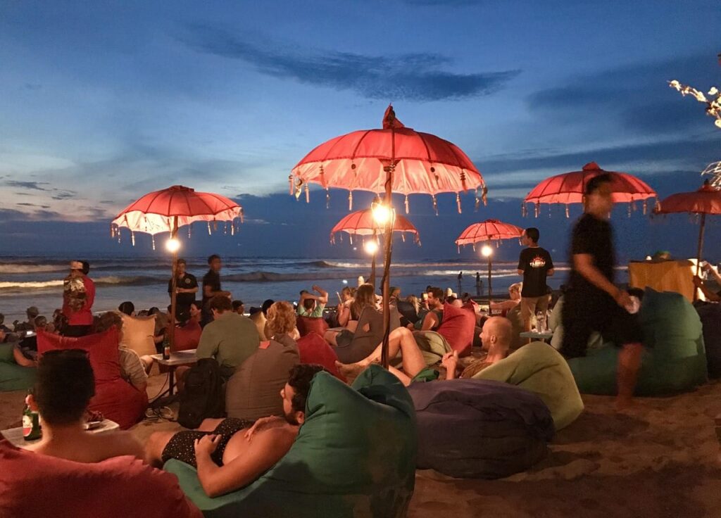 people laying on sofas on the beach at Seminyak, Bali, Indonesia.