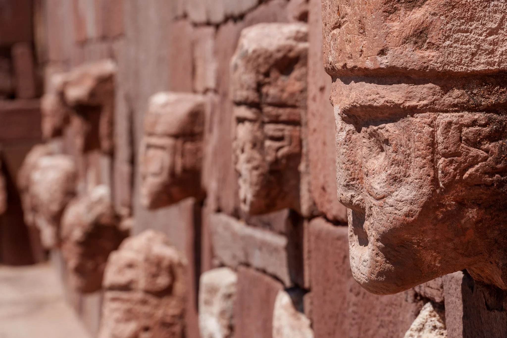 Close up of a statue coming out of a wall at Tiwanaku archeological site in Bolivia. There are many statues all over the wall like that.