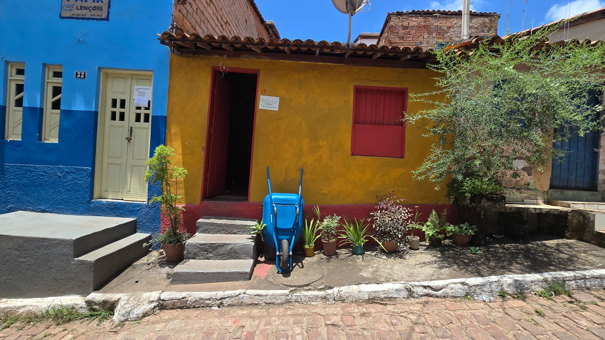 yellow house with red window and a blue house on the inside and blue a wheelbarrow, lencois, Brazil.